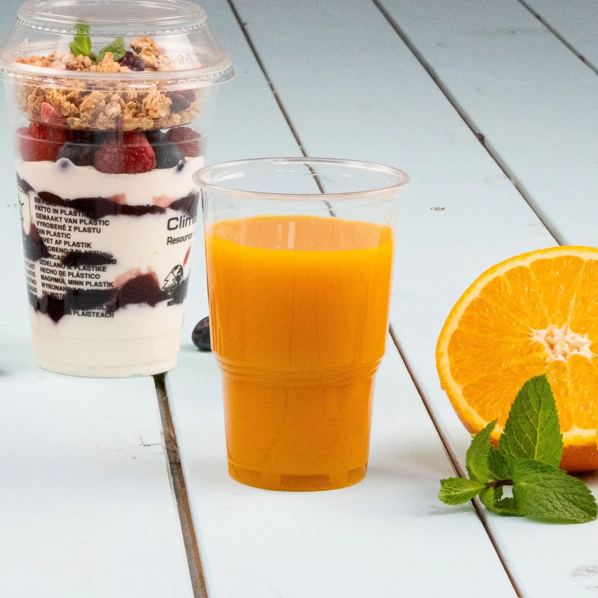 Un PLACup biodegradabile trasparente, 250 ml, progettato per bevande fredde; mostrato parzialmente sotto tazze simili.