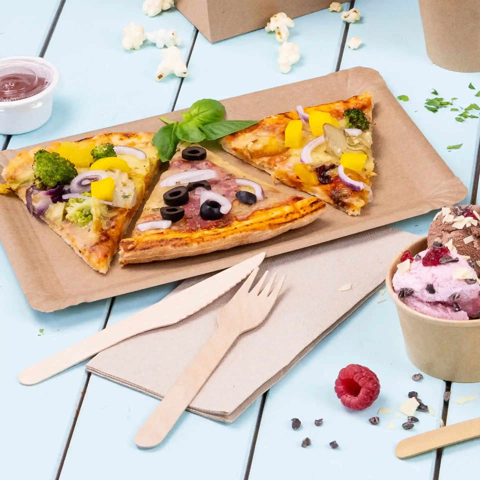 Immagine di tre fette di pizza su un vassoio di carta marrone, con posate di legno e un bicchiere di gelato vicino.