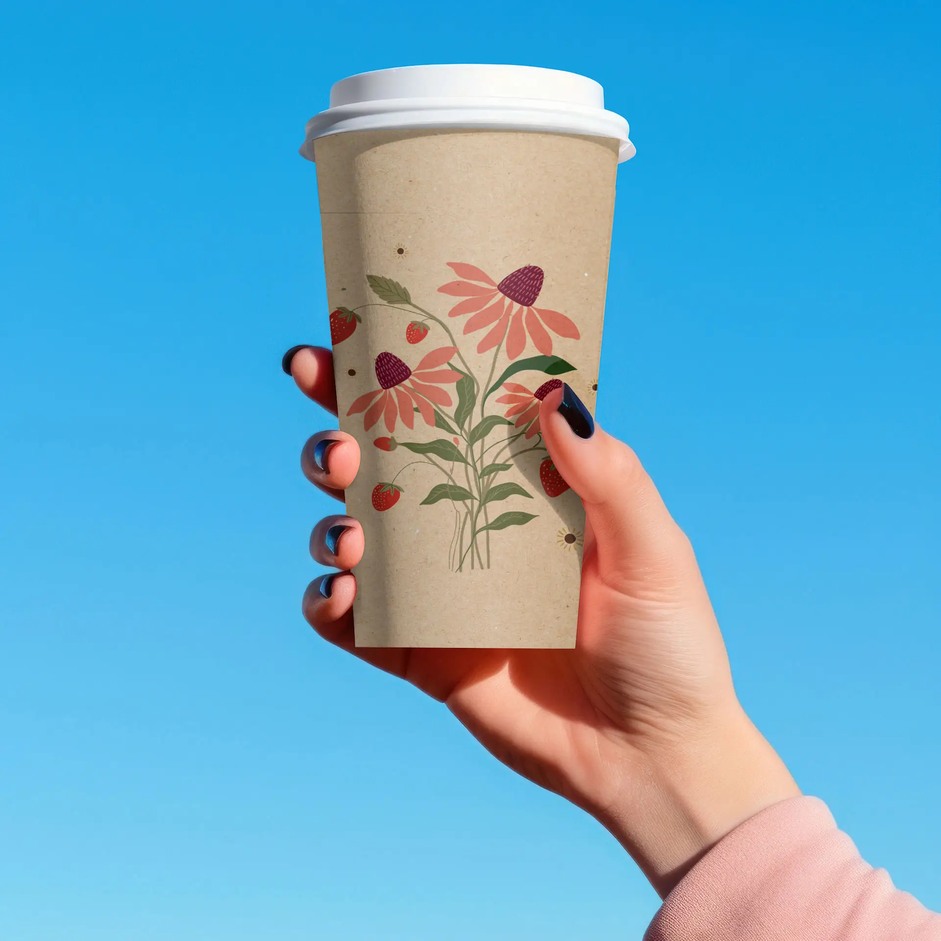 Una tazza di carta marrone con design floreali in mano contro uno sfondo di cielo blu.