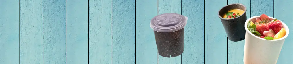 Personaggio cartoon verde con occhiali da sole, tiene un drink e un telefono, con ciotole di cibo su uno sfondo in legno blu.