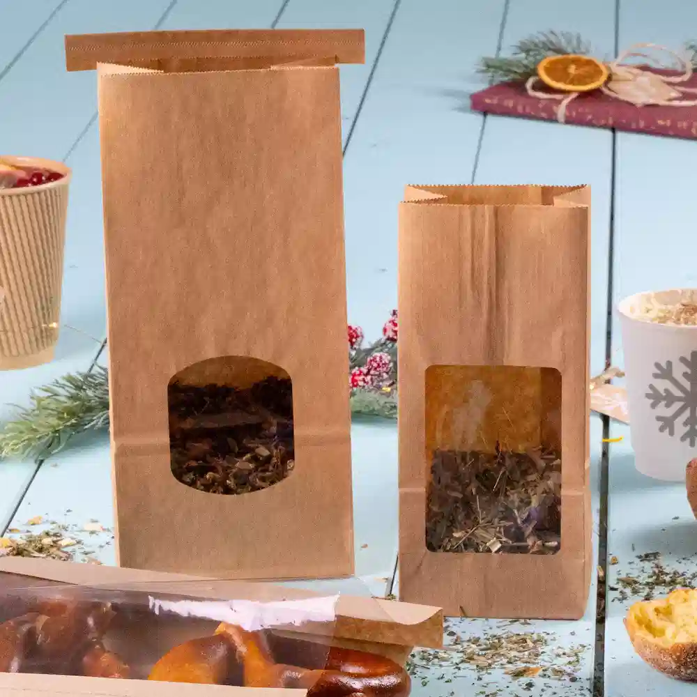 Due borse di carta marrone con finestre trasparenti, una più grande e una più piccola, contenenti erbe o foglie di tè.