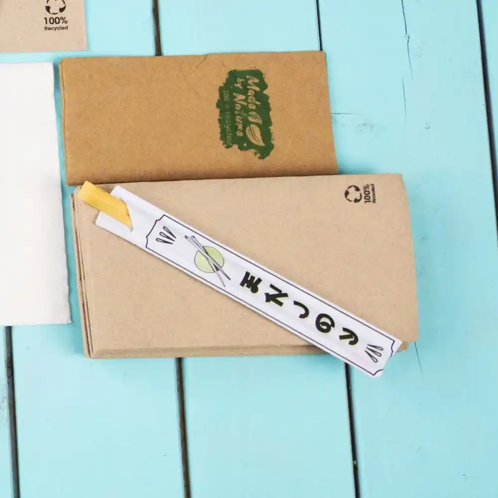 Bastoncini avvolti in carta su una superficie di legno blu, con una scatola di carta kraft marrone sullo sfondo.