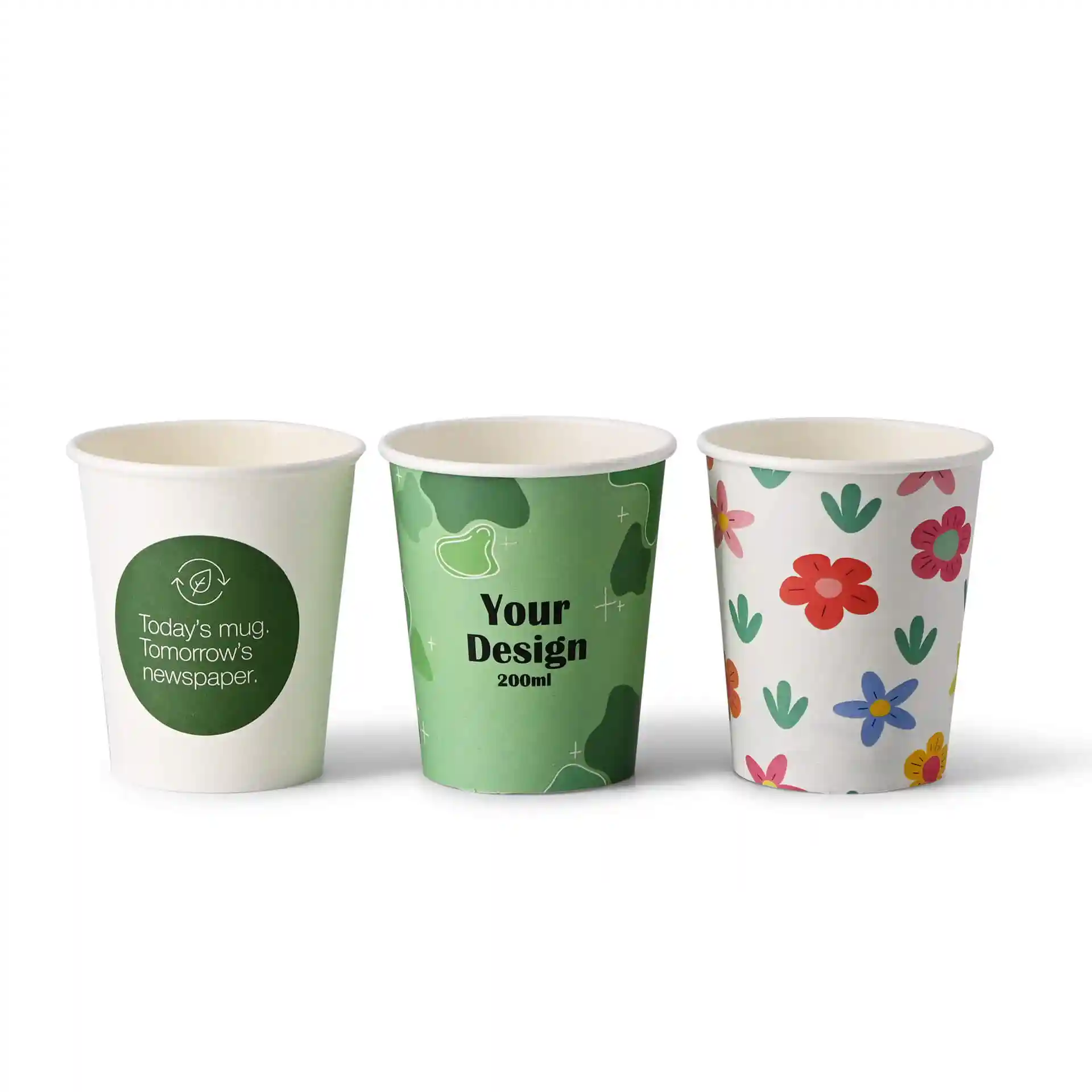 Tre bicchieri di carta con design diversi: uno con un logo verde, uno con un motivo verde e uno con fiori colorati.
