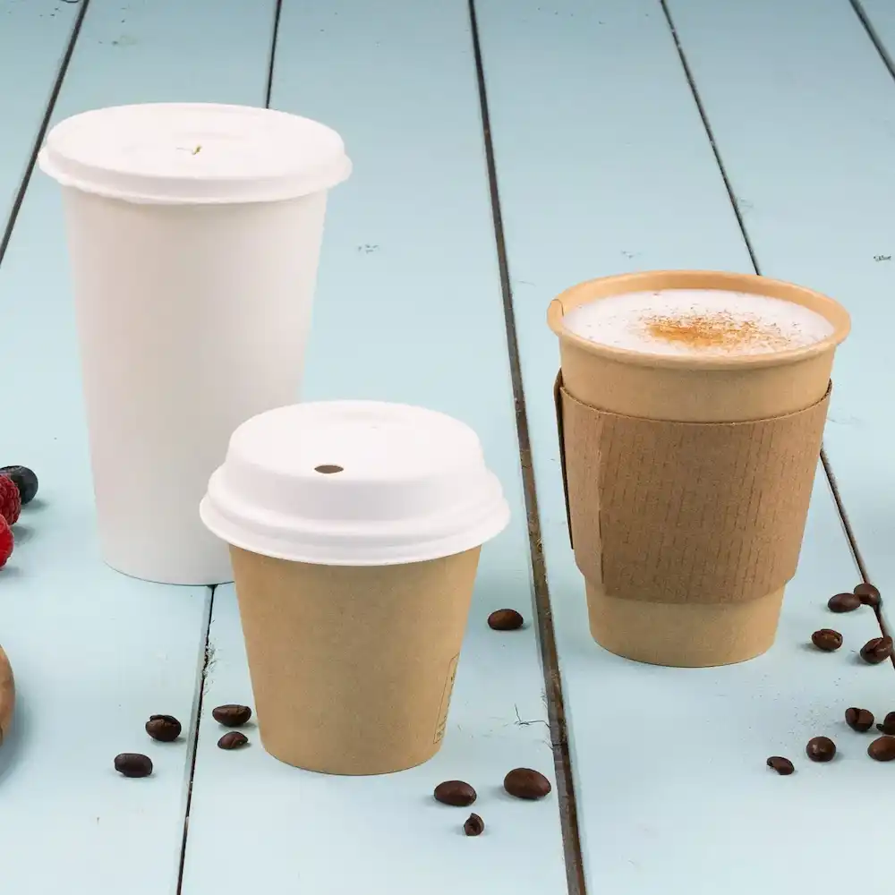Tre bicchieri di carta usa e getta di diverse dimensioni: un grande bicchiere bianco, un medio bicchiere marrone e un piccolo bicchiere marrone con manica.