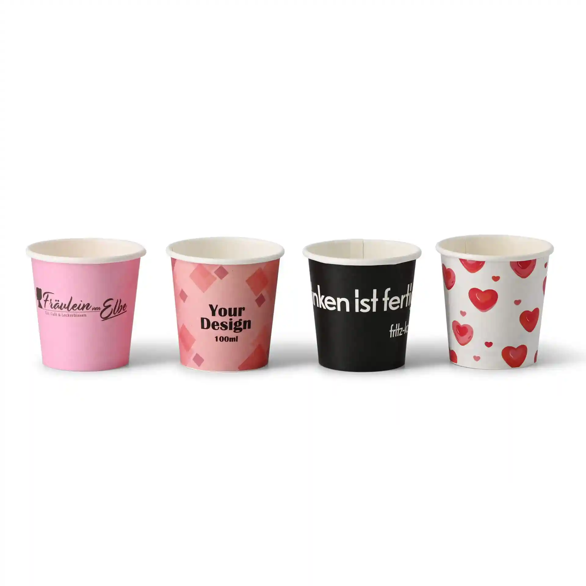 Quattro bicchieri di carta con vari design: rosa con logo, rosa a motivo geometrico, nero con testo e bianco con cuori.
