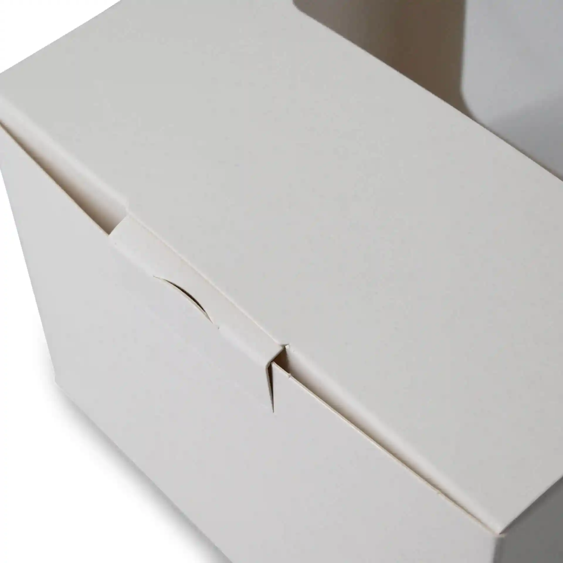 Scatola per dolci bianca con finestra in cellulosa, mostra la chiusura superiore e parte del lato. Dimensioni: 13 x 11 x 8 cm.