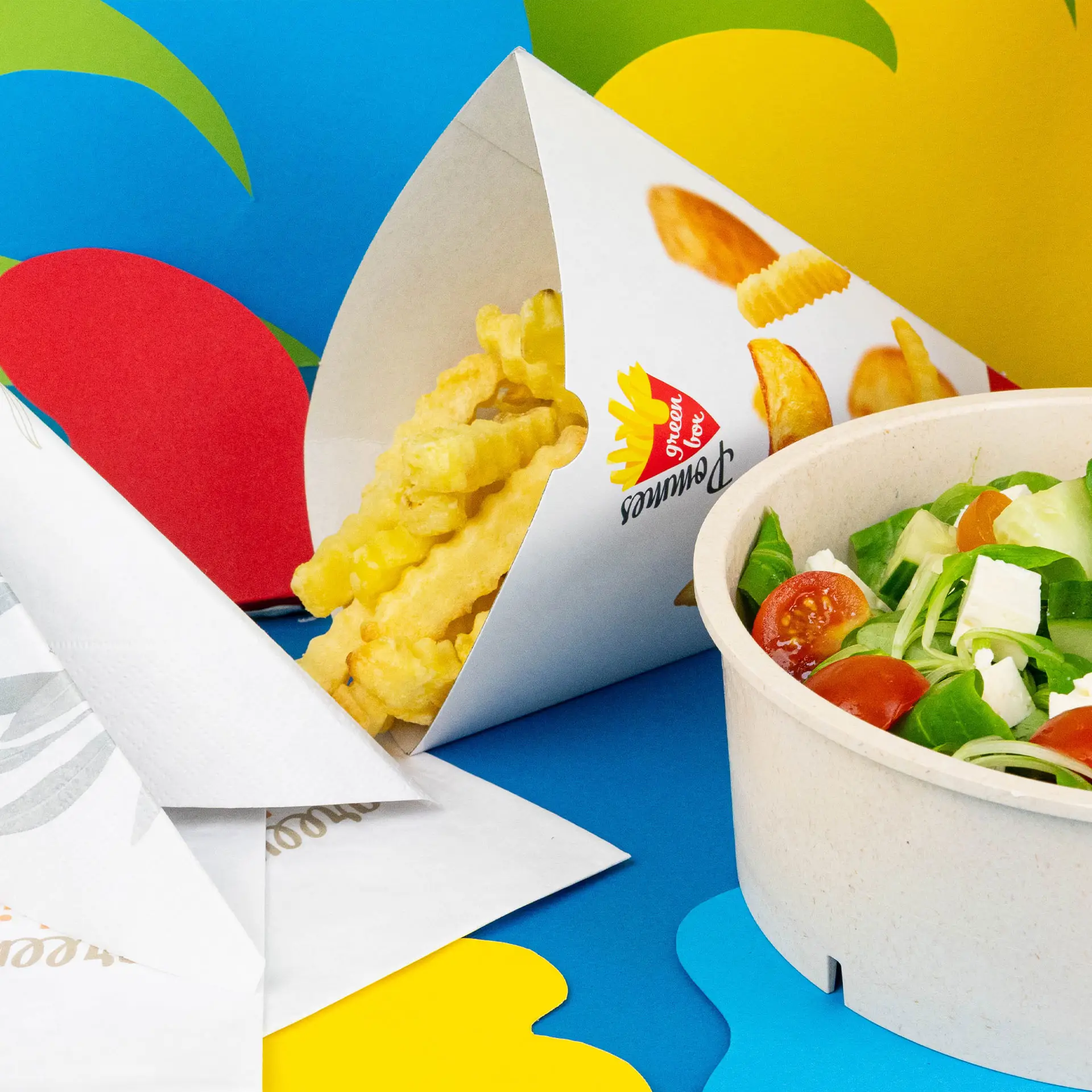 Immagine di un cono per patatine fritte bianco stampato con patatine arricciate e un'insalata in un contenitore rotondo su uno sfondo colorato.