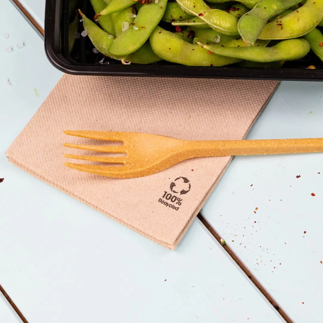 Tovagliolo marrone con una forchetta gialla sopra, accanto a un contenitore nero di fagioli edamame.