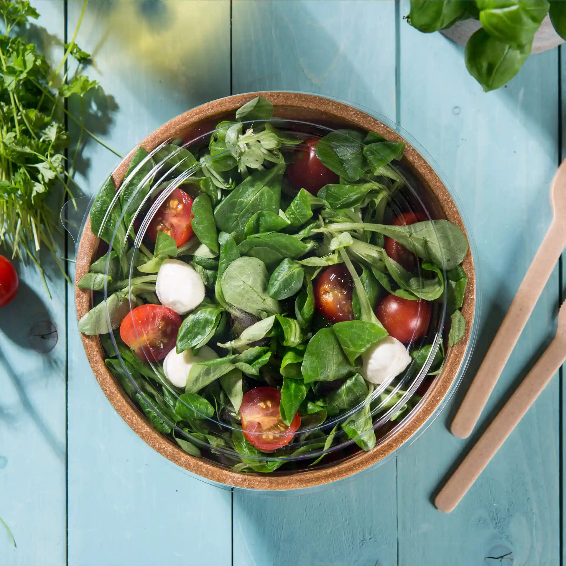Coperchio rotondo trasparente in PLA, posizionato su una ciotola di insalata con pomodorini e verdure.