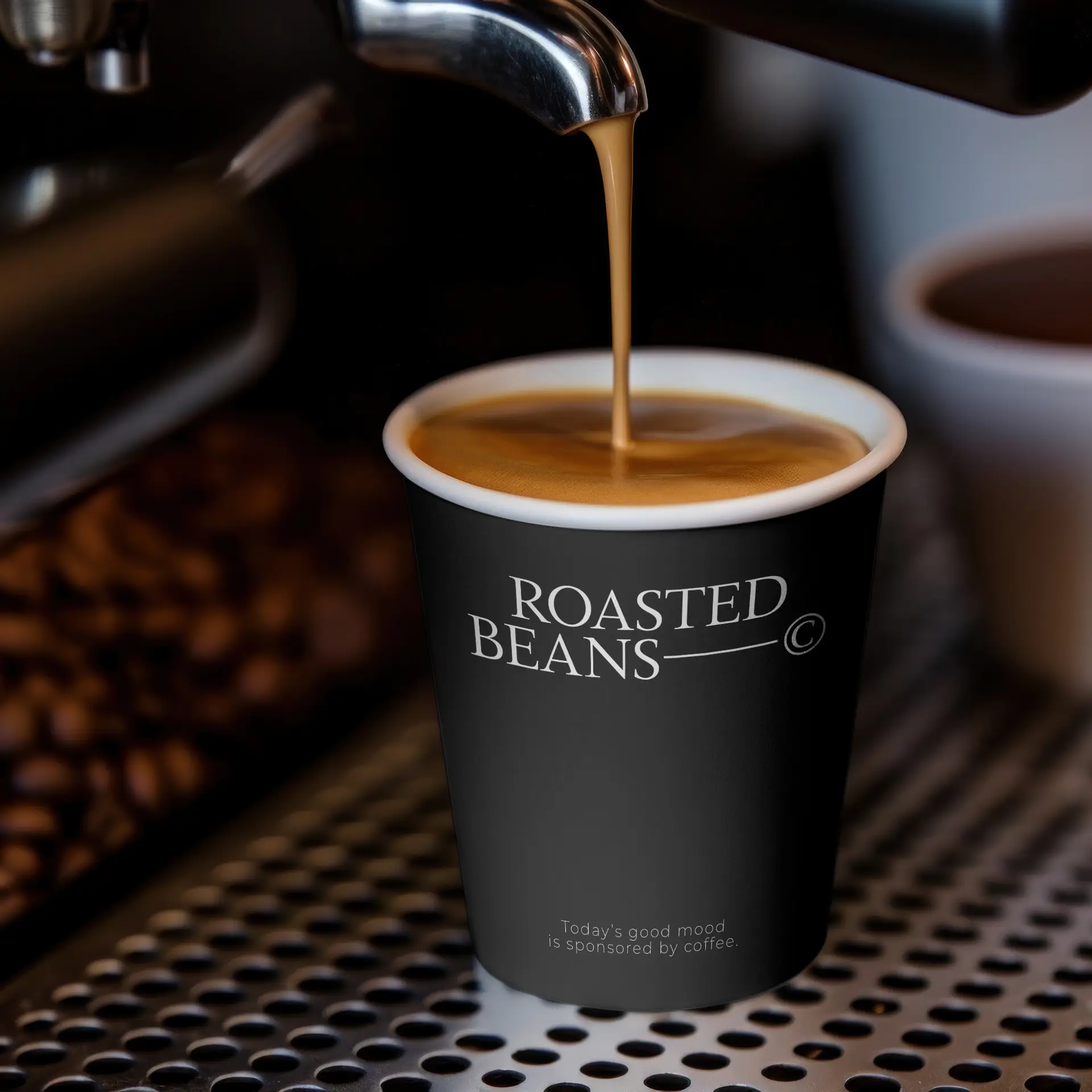 Una tazza piena di caffè, con un design nero con la scritta "ROASTED BEANS", è posata su una superficie metallica.