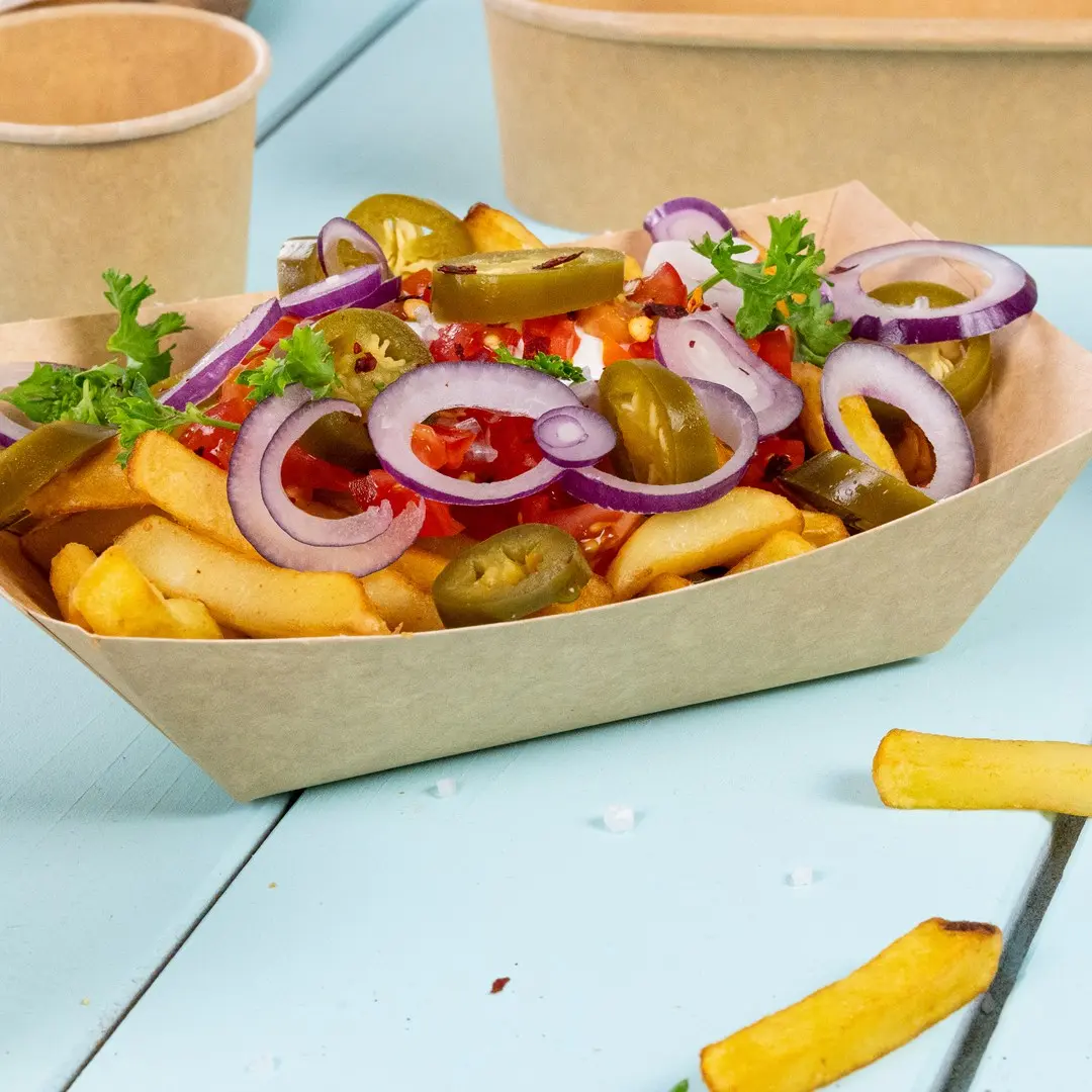 Ciotola di patatine fritte guarnita con cipolle affettate, jalapeños, pomodori a cubetti e prezzemolo su una superficie blu.