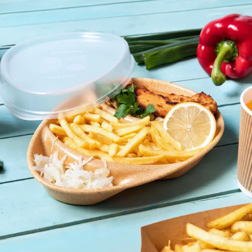 Contenitore per alimenti con pesce fritto, limone, patatine e insalata, accompagnato da cipollotti e un peperone rosso.