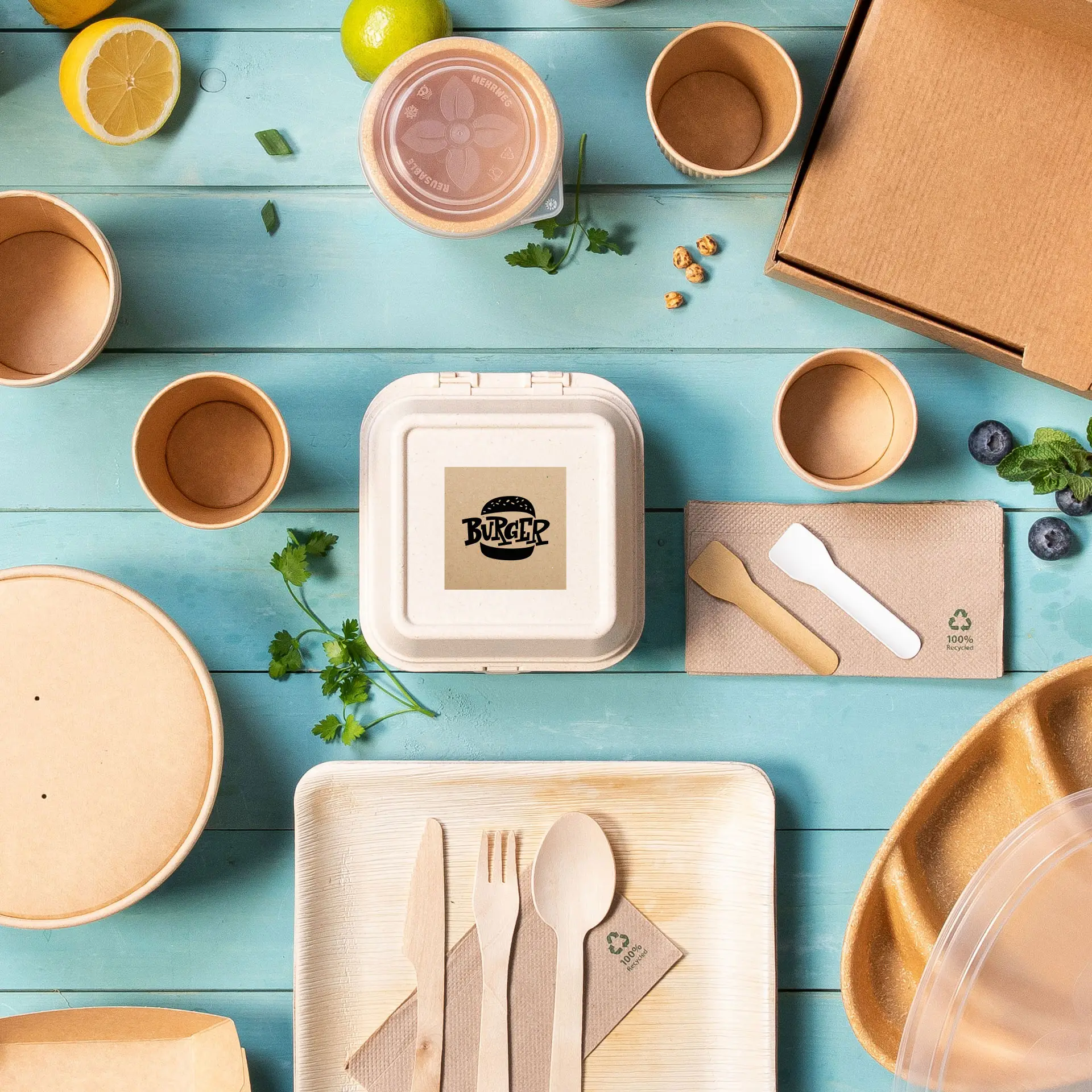 Un contenitore quadrato in carta kraft con un logo di hamburger, circondato da vari imballaggi alimentari usa e getta e posate.