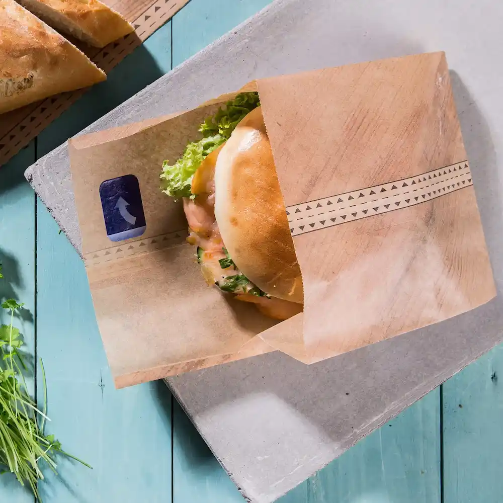 Wrap contenente un panino con lattuga e altri ingredienti su una superficie in legno blu.