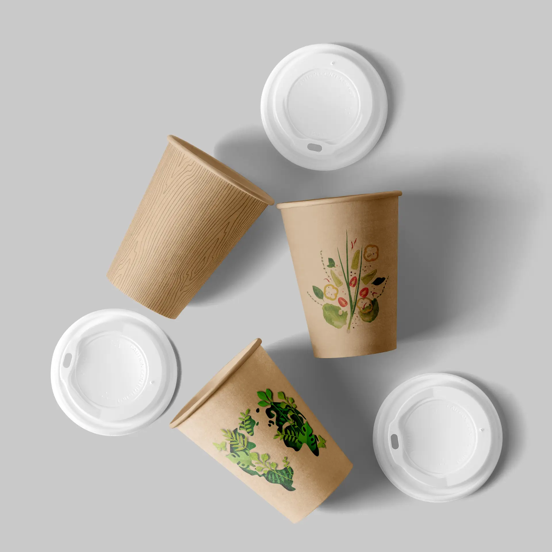 Un bicchiere di carta marrone con un design a venature di legno; due bicchieri con motivi floreali e fogliari colorati; due coperchi bianchi sopra.