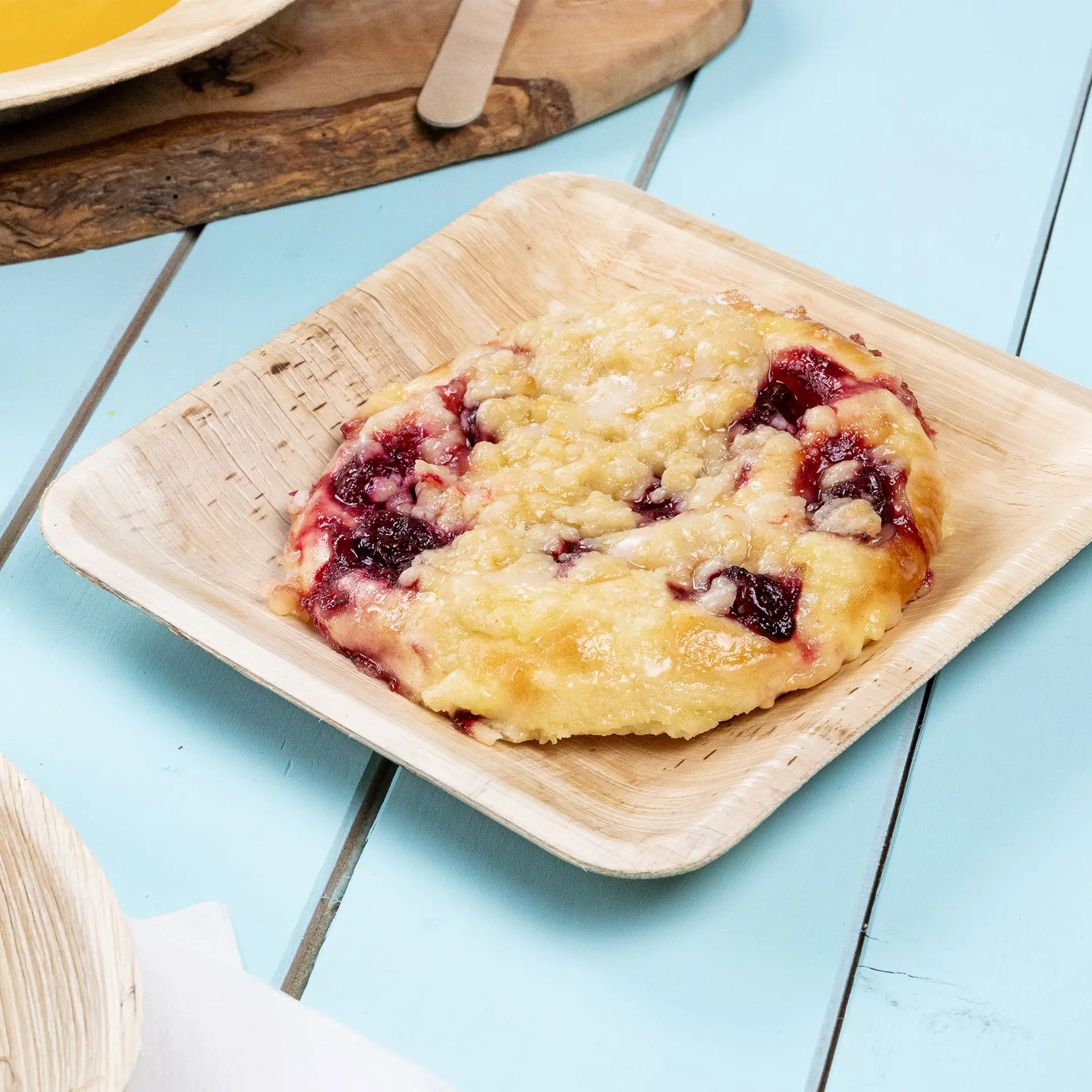 Un piatto quadrato in foglia di palma con un dessert cotto ripieno di frutti rossi; il piatto ha un aspetto con venature naturali.
