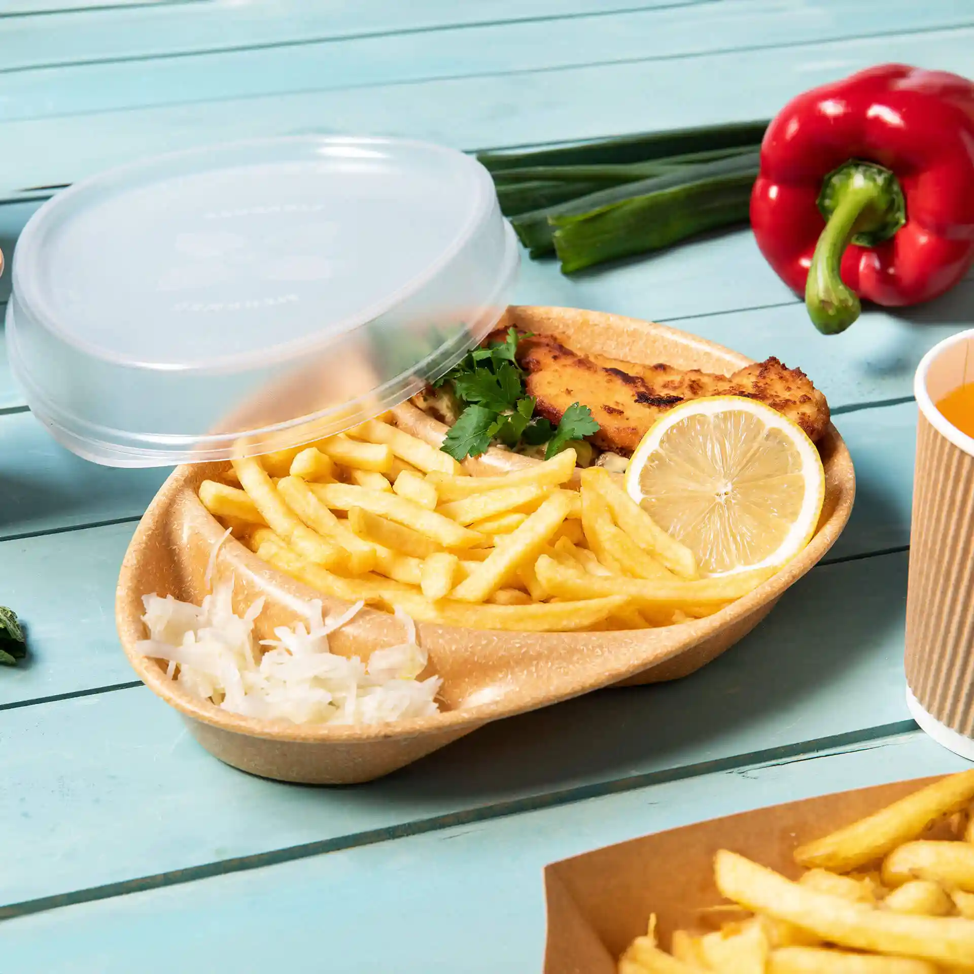 Piatto riutilizzabile marrone con tre scomparti, contenente patatine, pesce, limone e coriandolo, con un coperchio trasparente.