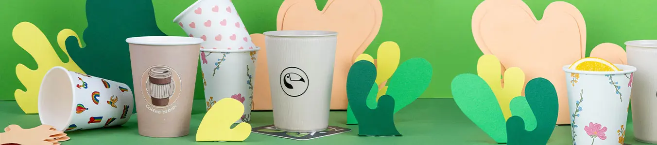 Immagine di diverse tazze stampate personalizzabili con ritagli di carta colorati su uno sfondo verde.