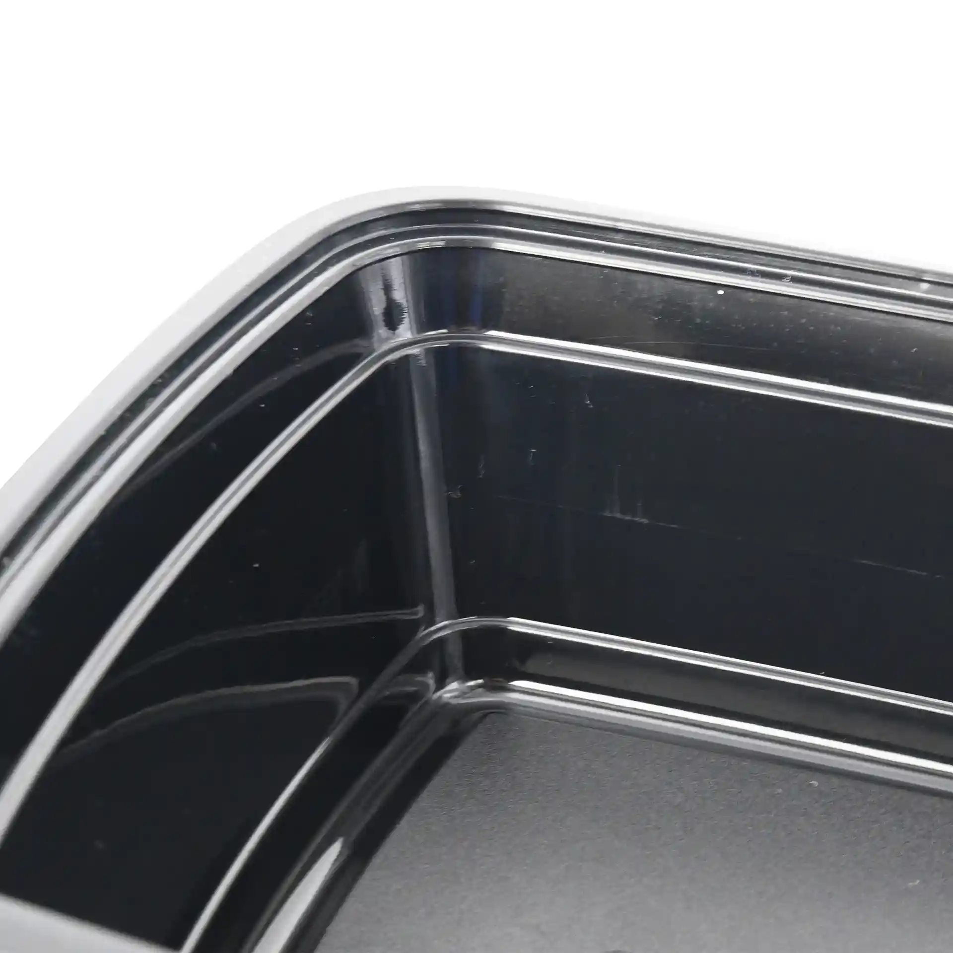 Primo piano di un contenitore rettangolare nero riutilizzabile con angoli e bordi interni visibili.