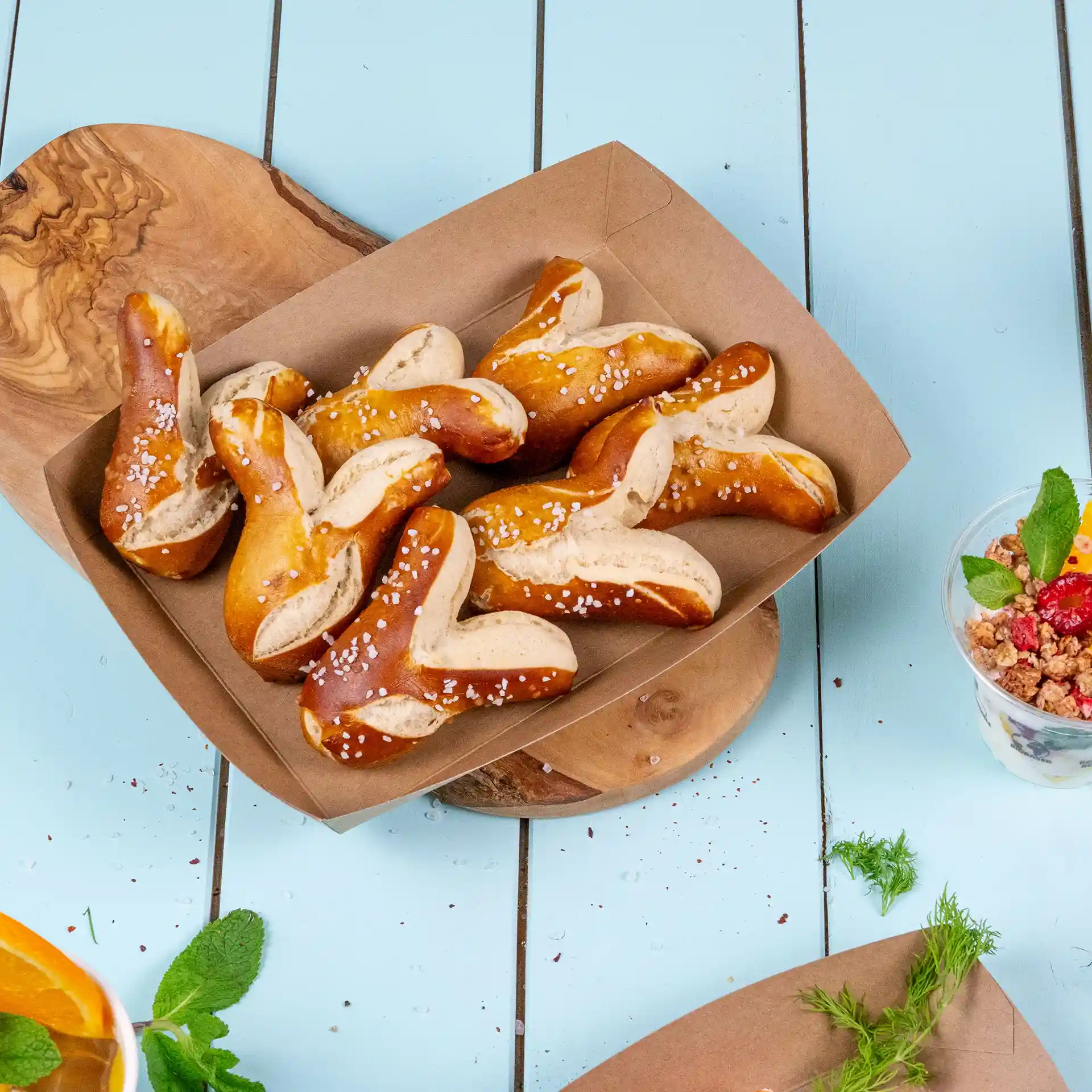 Un vassoio di cartone marrone pieno di diversi pezzi di pretzel guarniti con sale grosso.