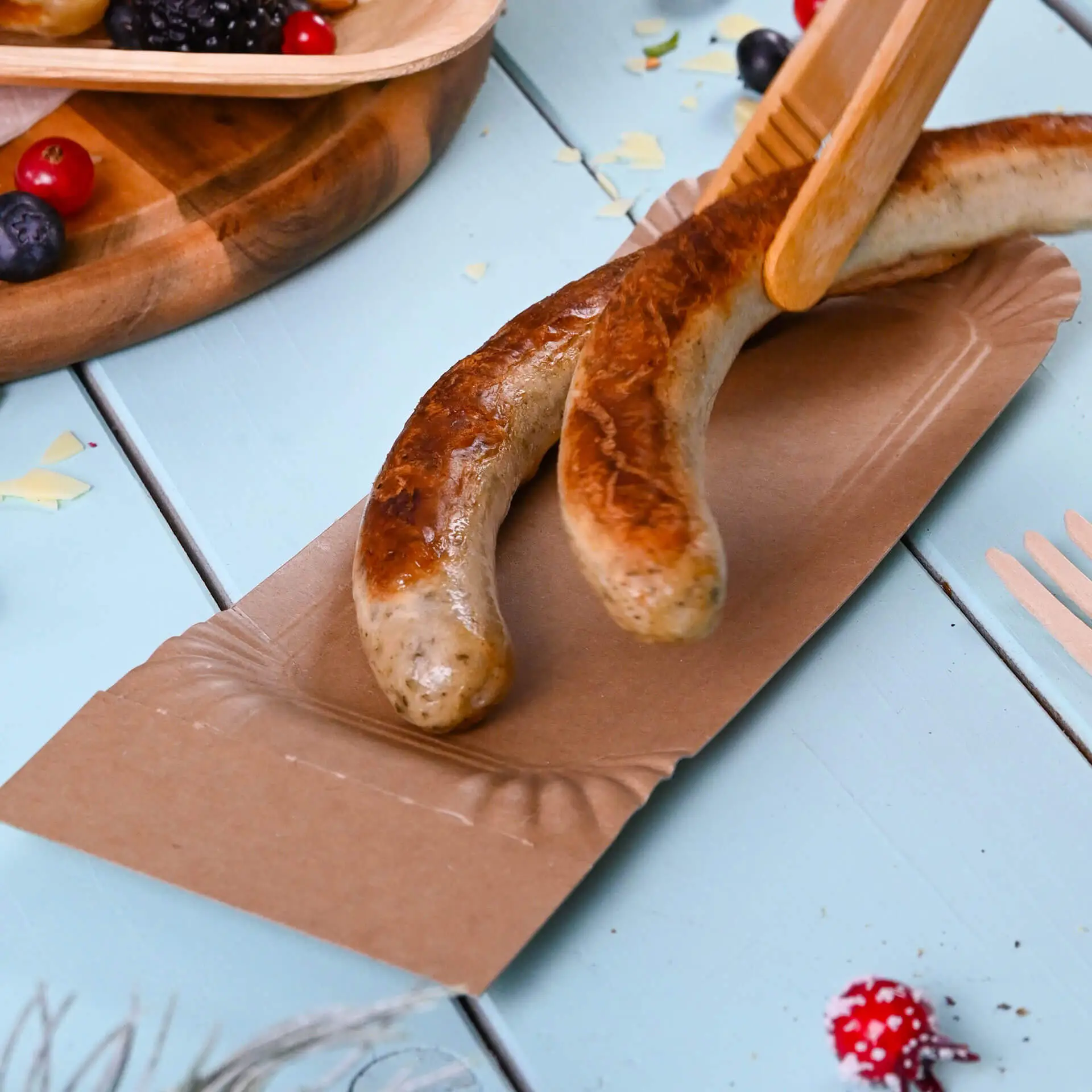 Due salsicce grigliate su un piatto di cartone strappabile; il piatto è marrone e rettangolare, adatto per servire snack.