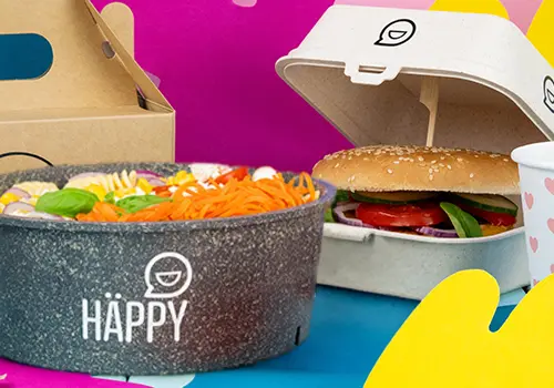 Mucchio di ciotole colorate etichettate "HAPPY BOWL" in vari design, con un contenitore per cibo separato sullo sfondo.