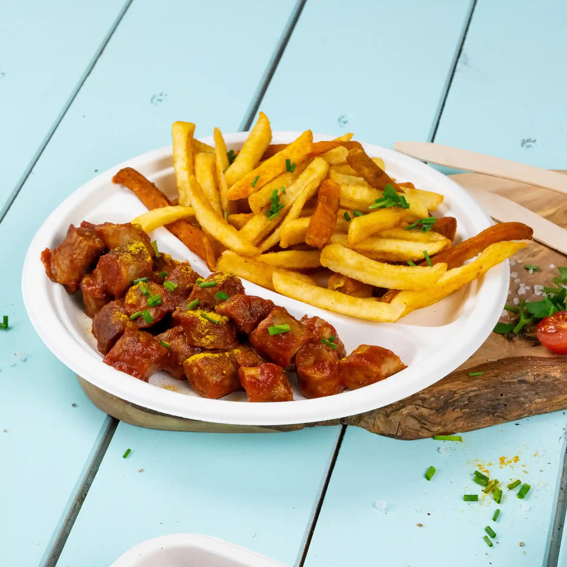 Piatto rotondo bianco in canna da zucchero con due scomparti, uno riempito con carne a cubetti in salsa e l'altro con patatine.