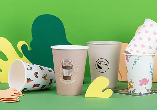 Vari diversi bicchieri su una superficie blu chiaro, con diverse grafiche ed etichette, tra cui "Alma & Auer" e "Indie Roasters."