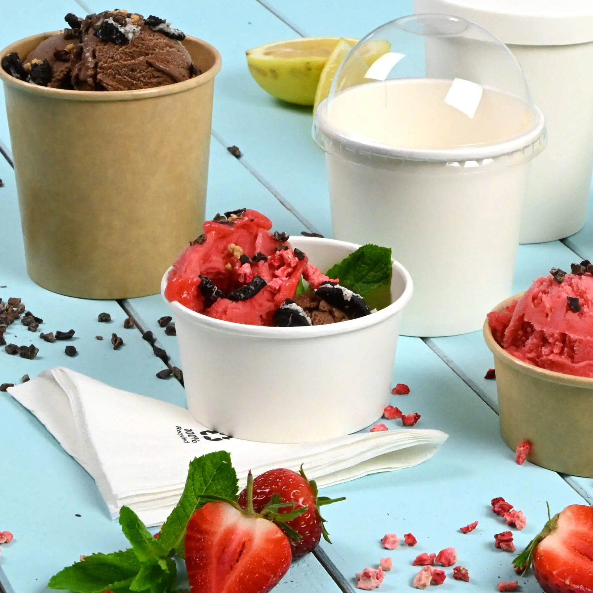 Una coppetta di carta bianca con gelato rosa e marrone guarnito con foglie di menta; un'altra coppetta marrone con gelato al cioccolato.