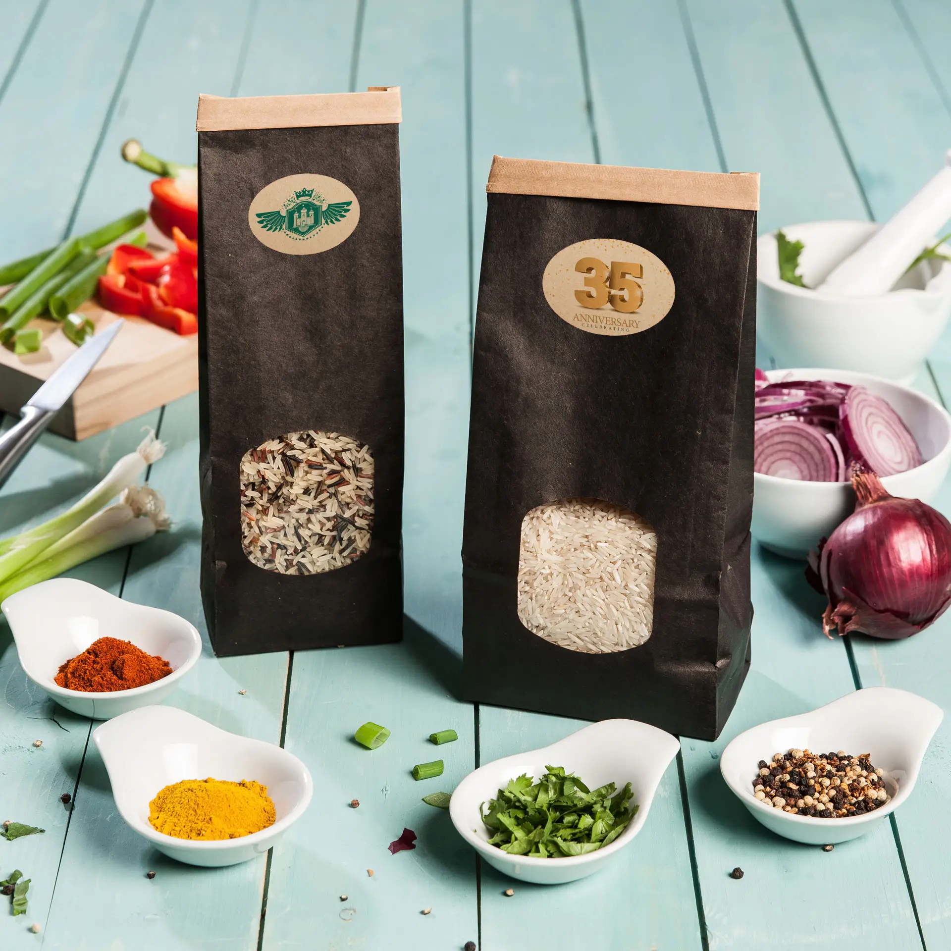 Due sacchetti di carta di riso, uno con riso basmati marrone e uno con riso bianco, posti su una superficie in legno blu con spezie sparse.