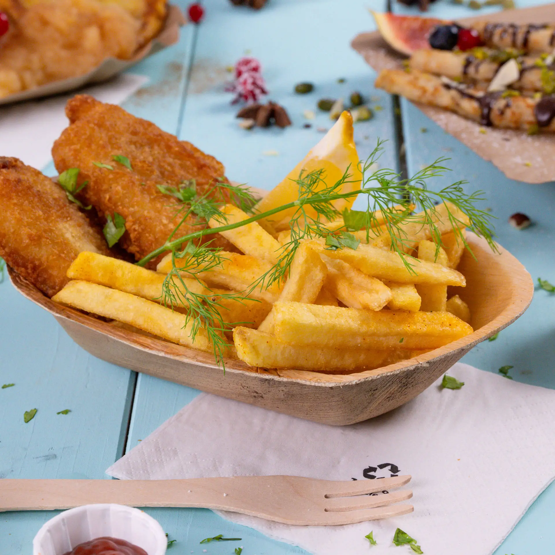 Filetti di pesce fritti e patatine dorate serviti in una barchetta di foglia di palma da 20 cm, guarniti con aneto e una fetta di limone.