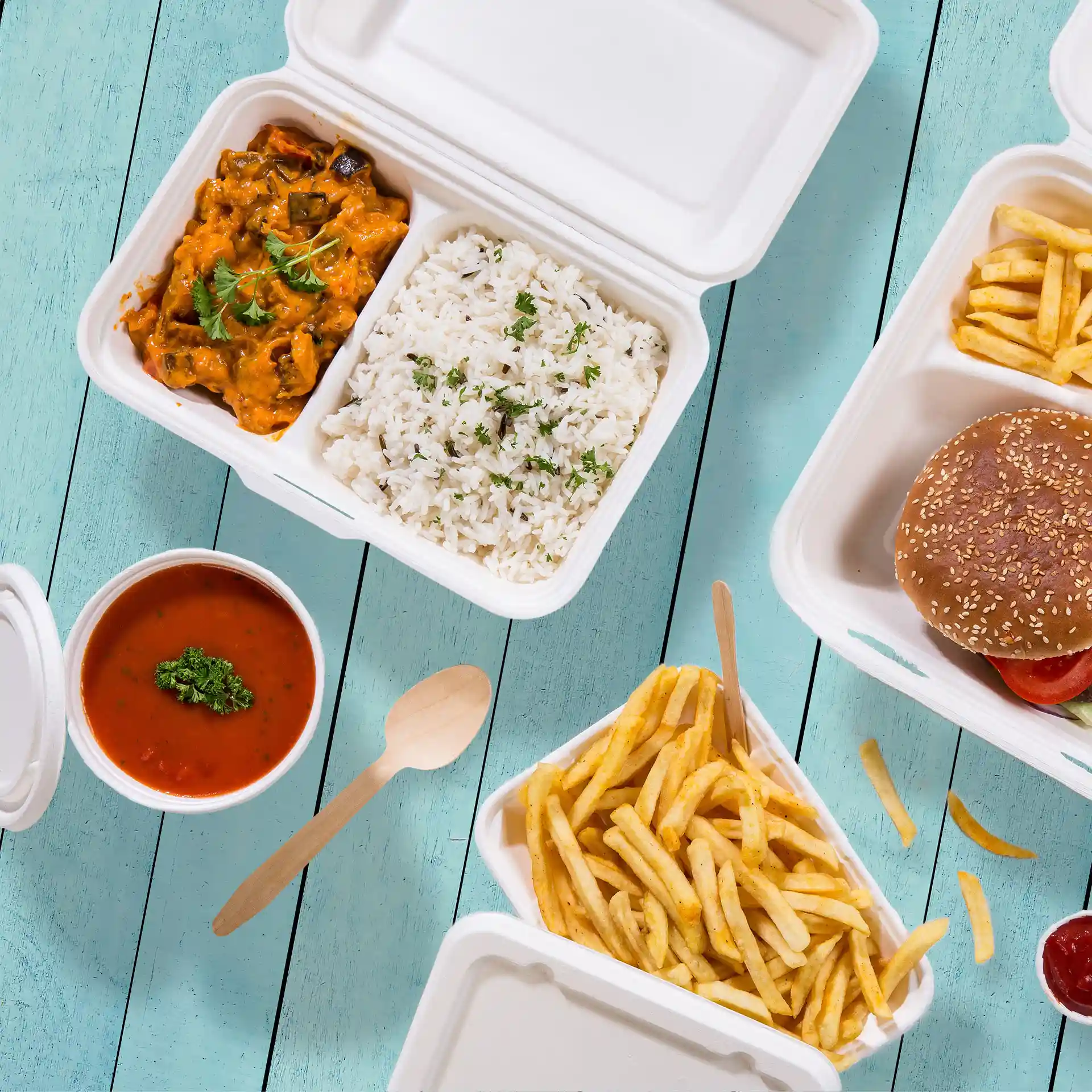Immagine di un contenitore in canna da zucchero bianco crema con due scomparti, contenente riso, curry, patatine e un hamburger.